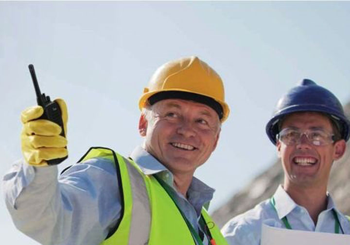 Site staff in hard hats and high-visibility gear with a two-way radio